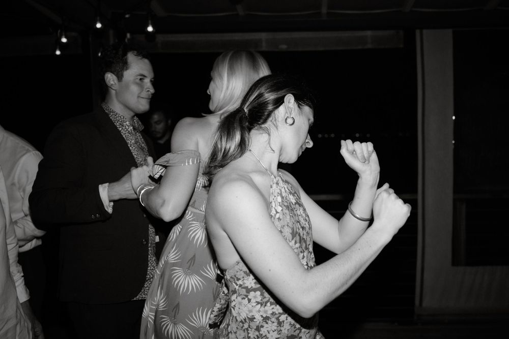 Black and white photo captures energetic dancing at a festive celebration.