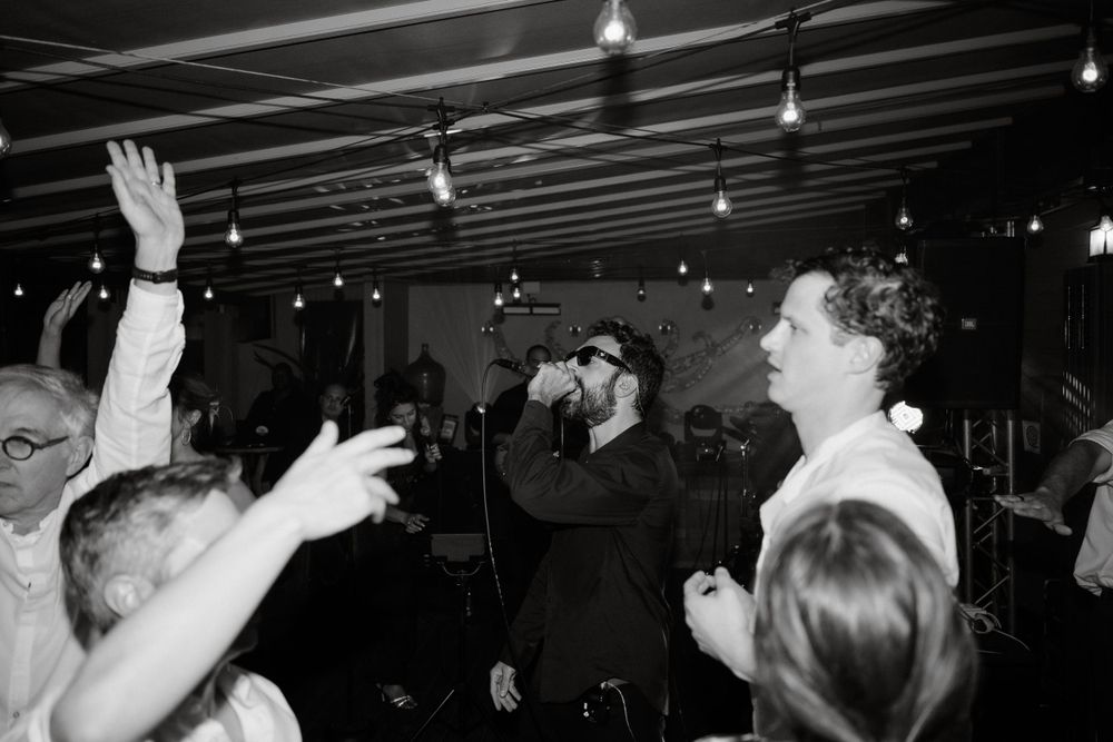Black and white shot of crowd dancing and celebrating at indoor reception.