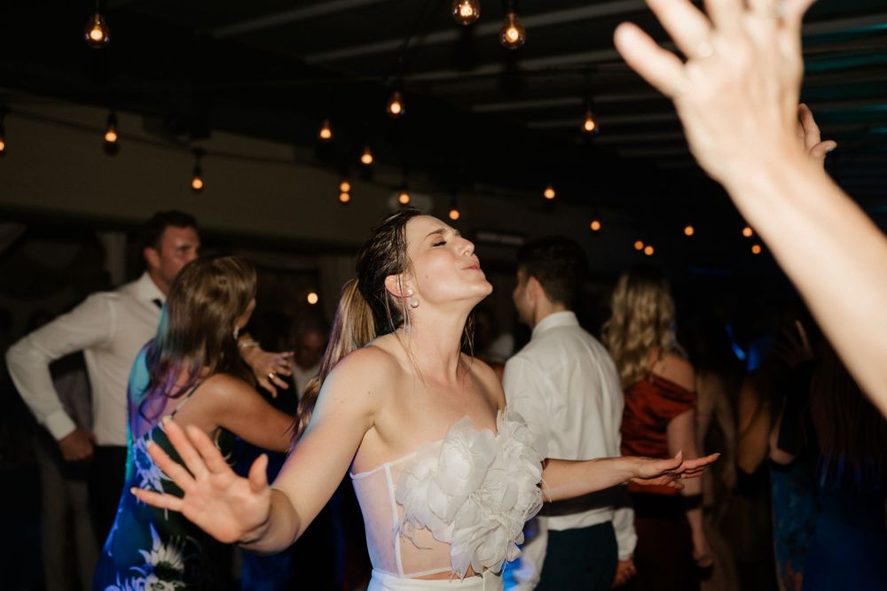 A wedding reception dance party with guests enjoying themselves under string lights.
