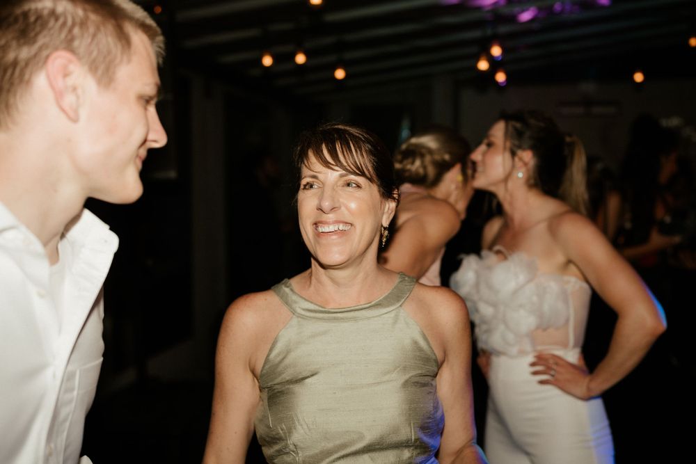 Guests dancing and enjoying themselves at a dimly lit wedding reception venue.