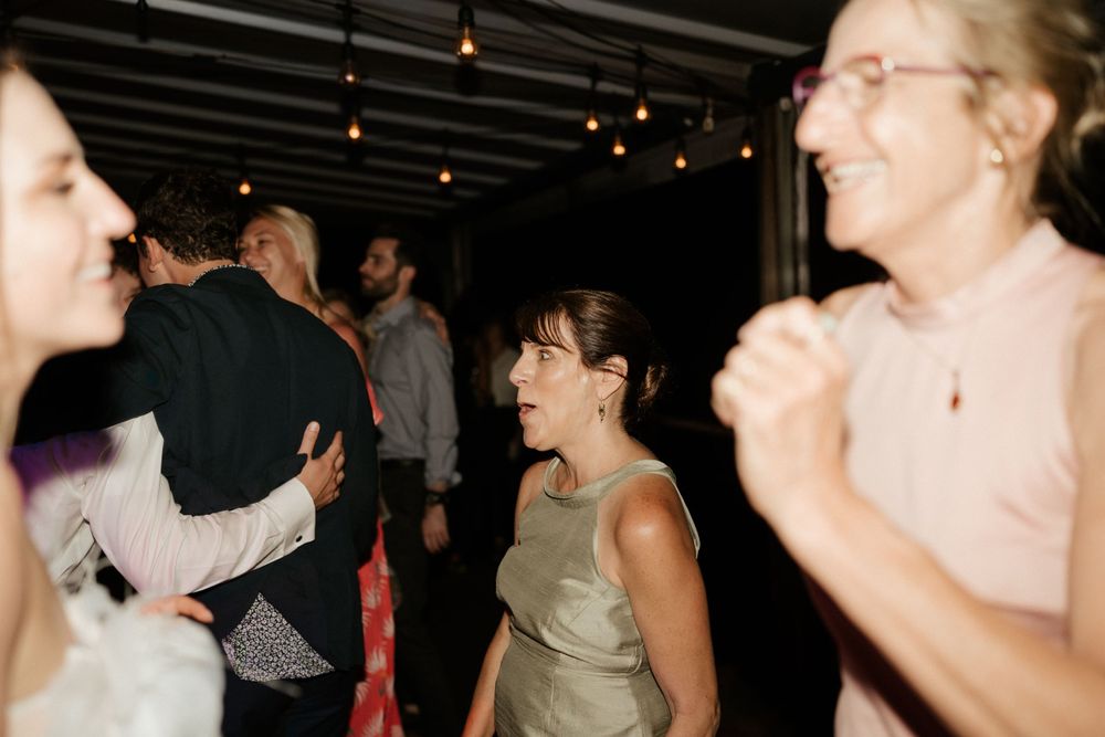 Candid photo of wedding guests dancing and laughing at a reception party.
