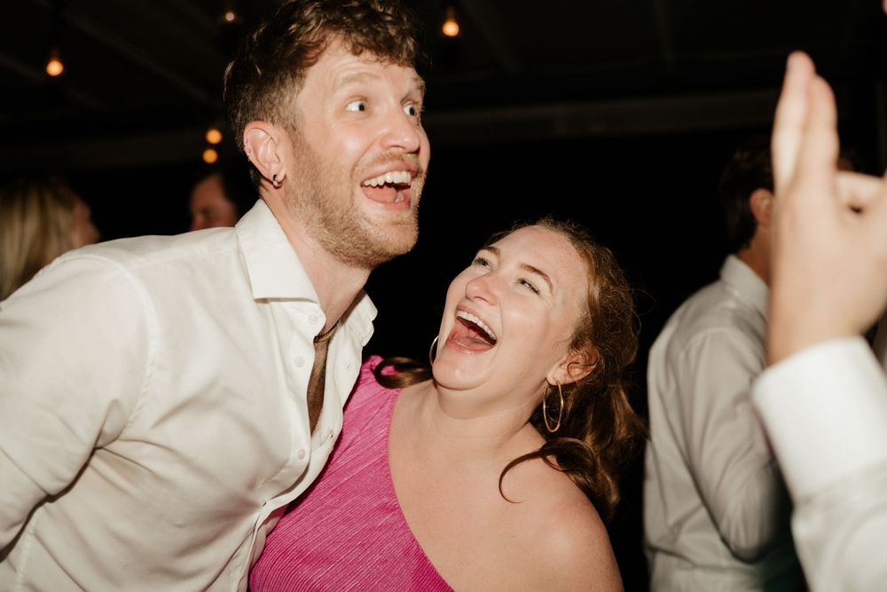 Candid moment captures pure joy and laughter on the dance floor at wedding reception.