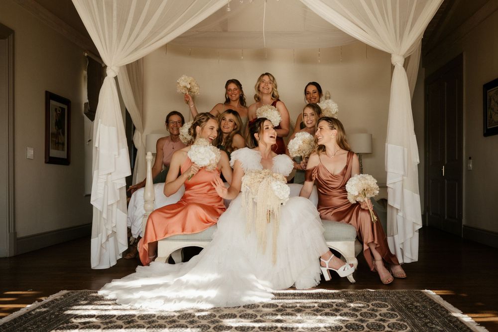 Wedding party portrait under white canopy with natural window lighting.