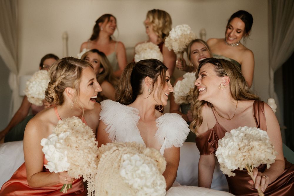 A celebratory wedding moment with bouquets of white flowers and blush pink dresses.