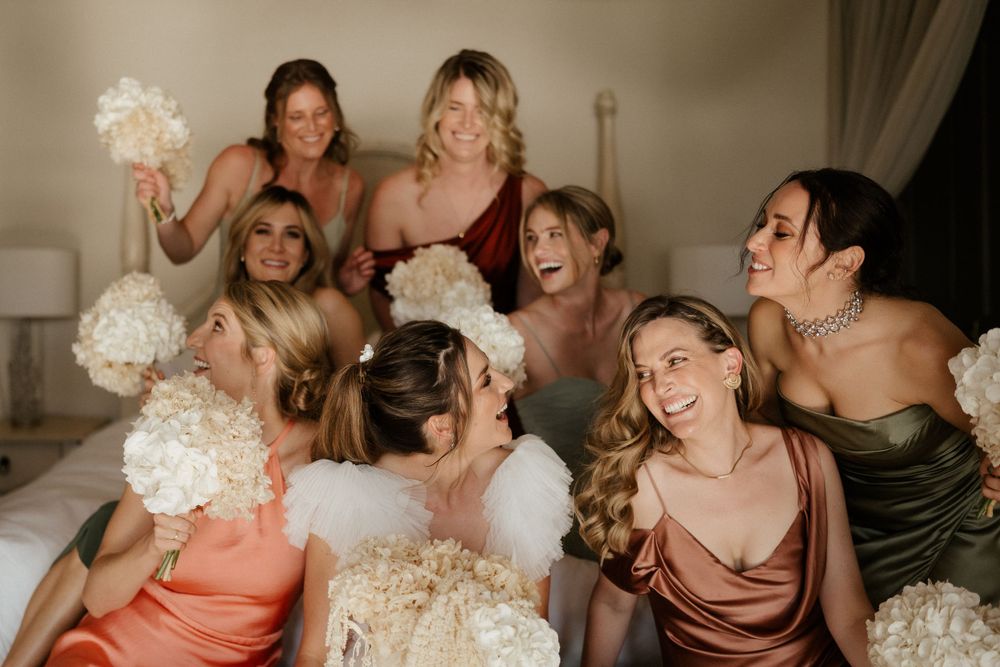 Joyful wedding party sharing a candid moment with bouquets.