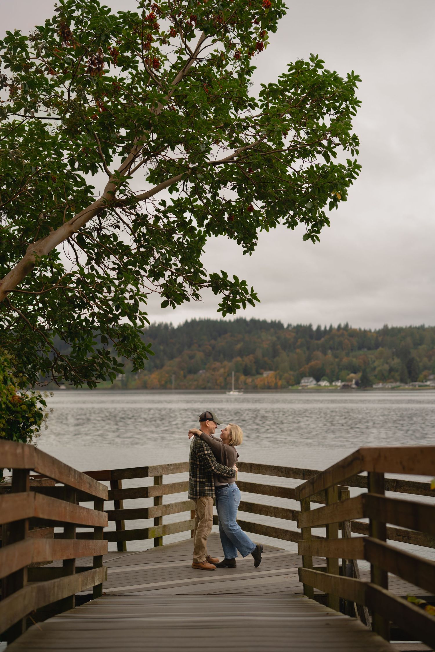 A romantic moment on a wooden dock overlooking a lake with autumn foliage.