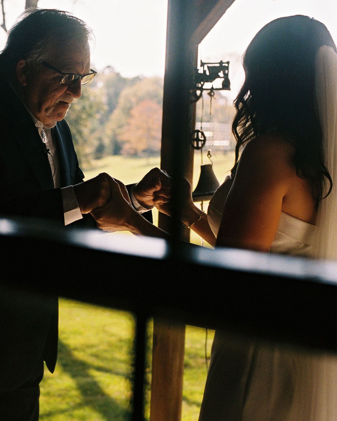 Silhouetted figures in elegant attire against a sunlit backdrop.