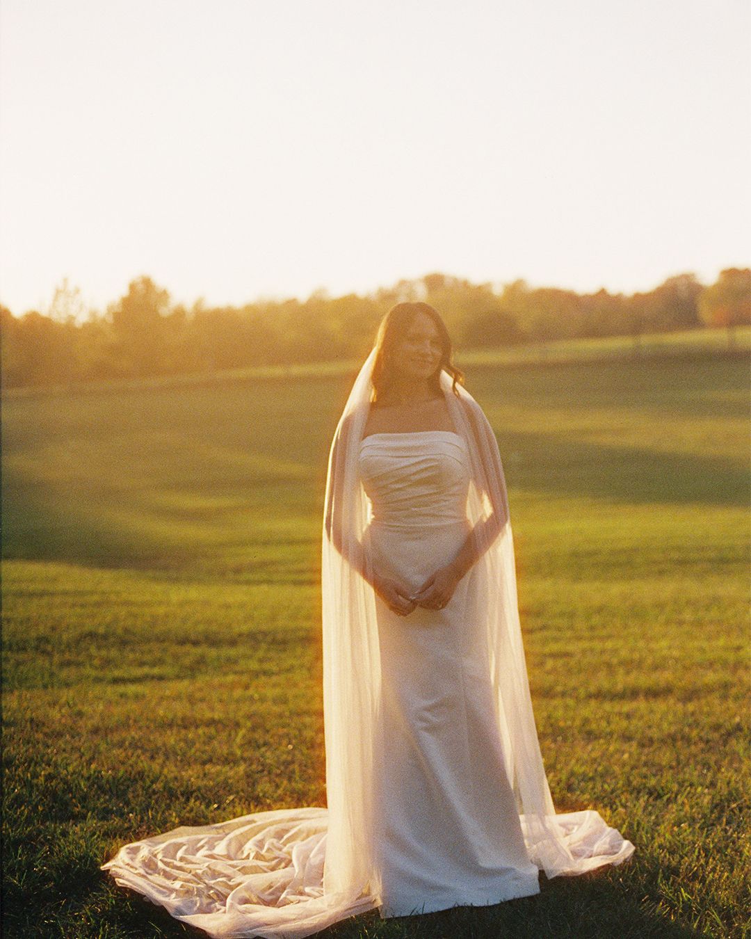 Ethereal sunset photo of flowing white wedding dress in a golden field.