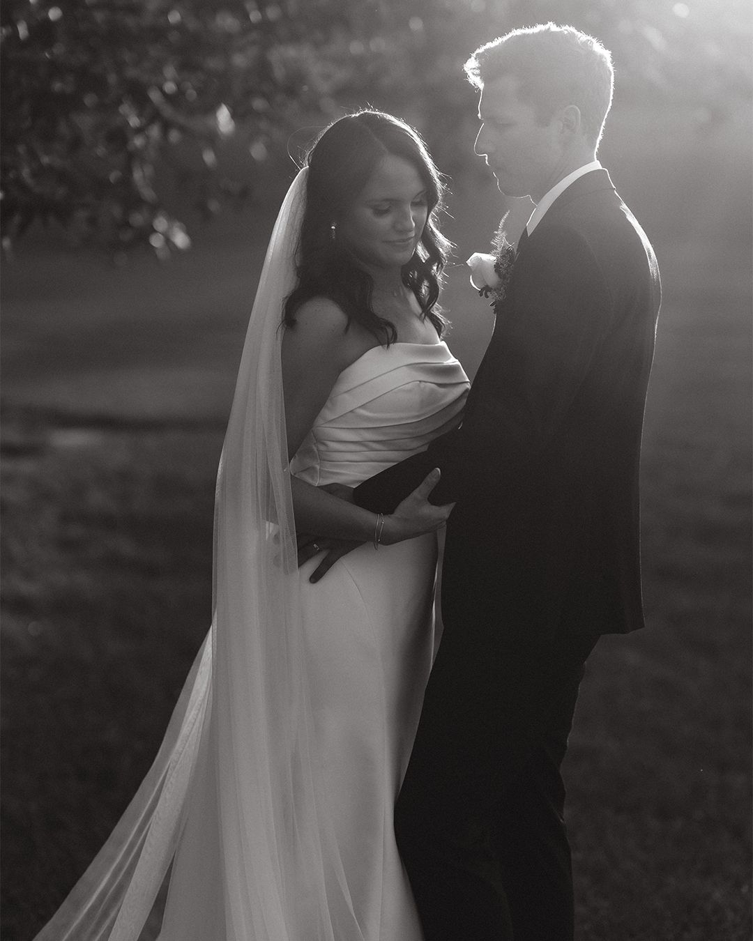 Black and white wedding portrait capturing a romantic dance in natural lighting.