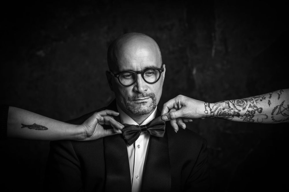 Black and white portrait series of a person in formal attire with glasses against dark background.