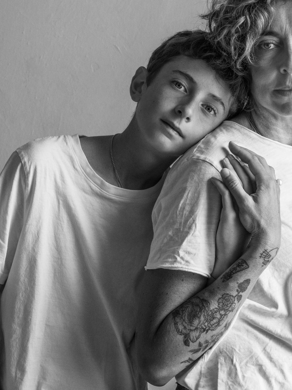Black and white portrait of two people in white t-shirts sharing a tender moment.