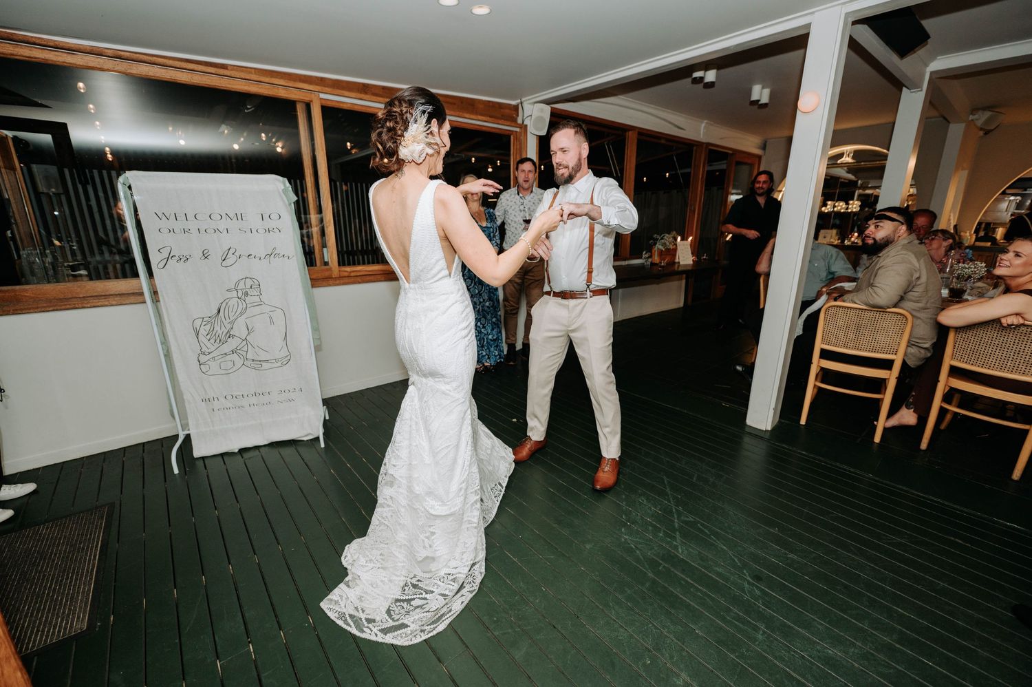 Couple dancing and twirling on green indoor dance floor during wedding reception.
