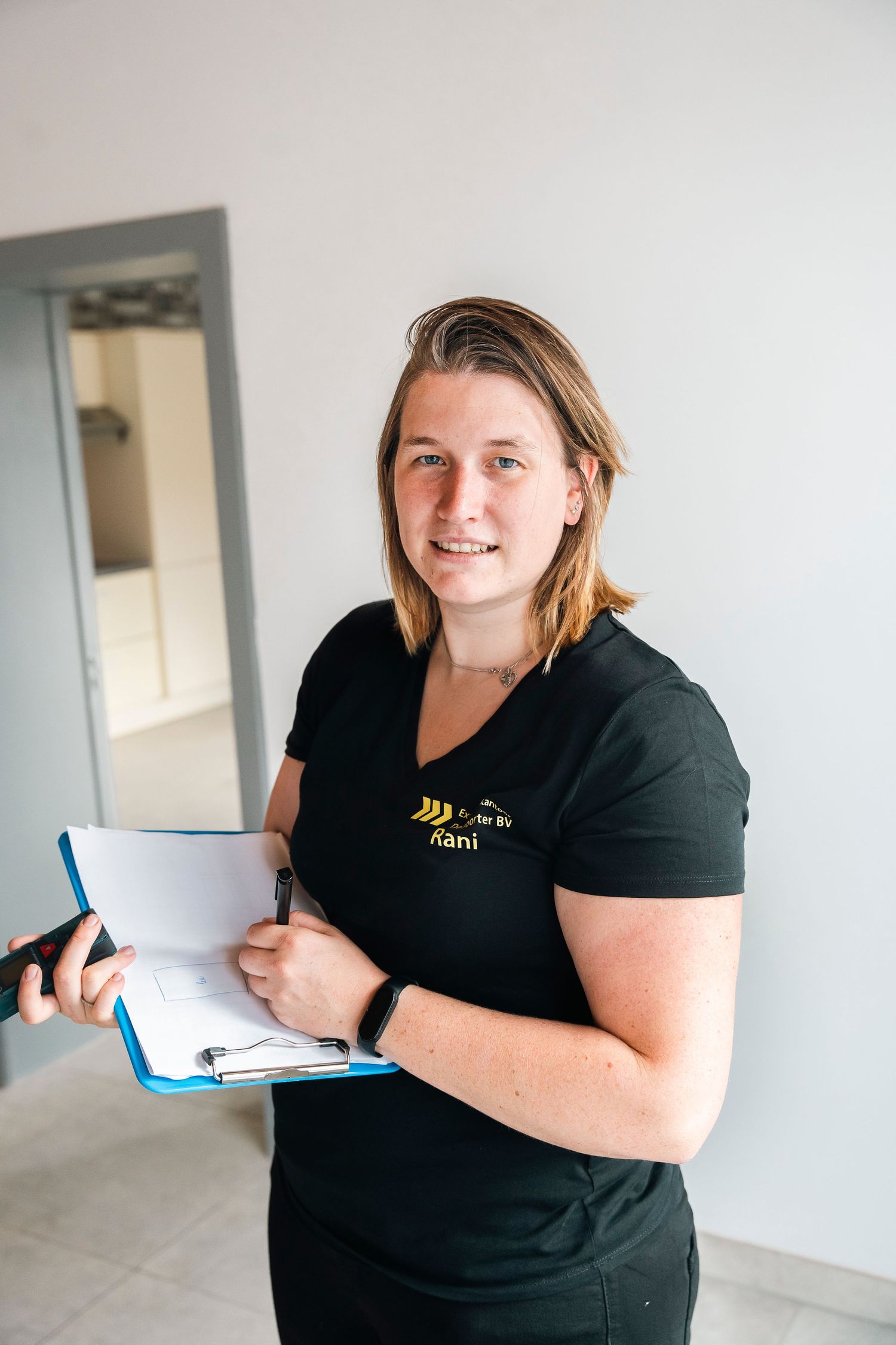 Professional in black uniform holding clipboard and pen while working indoors.