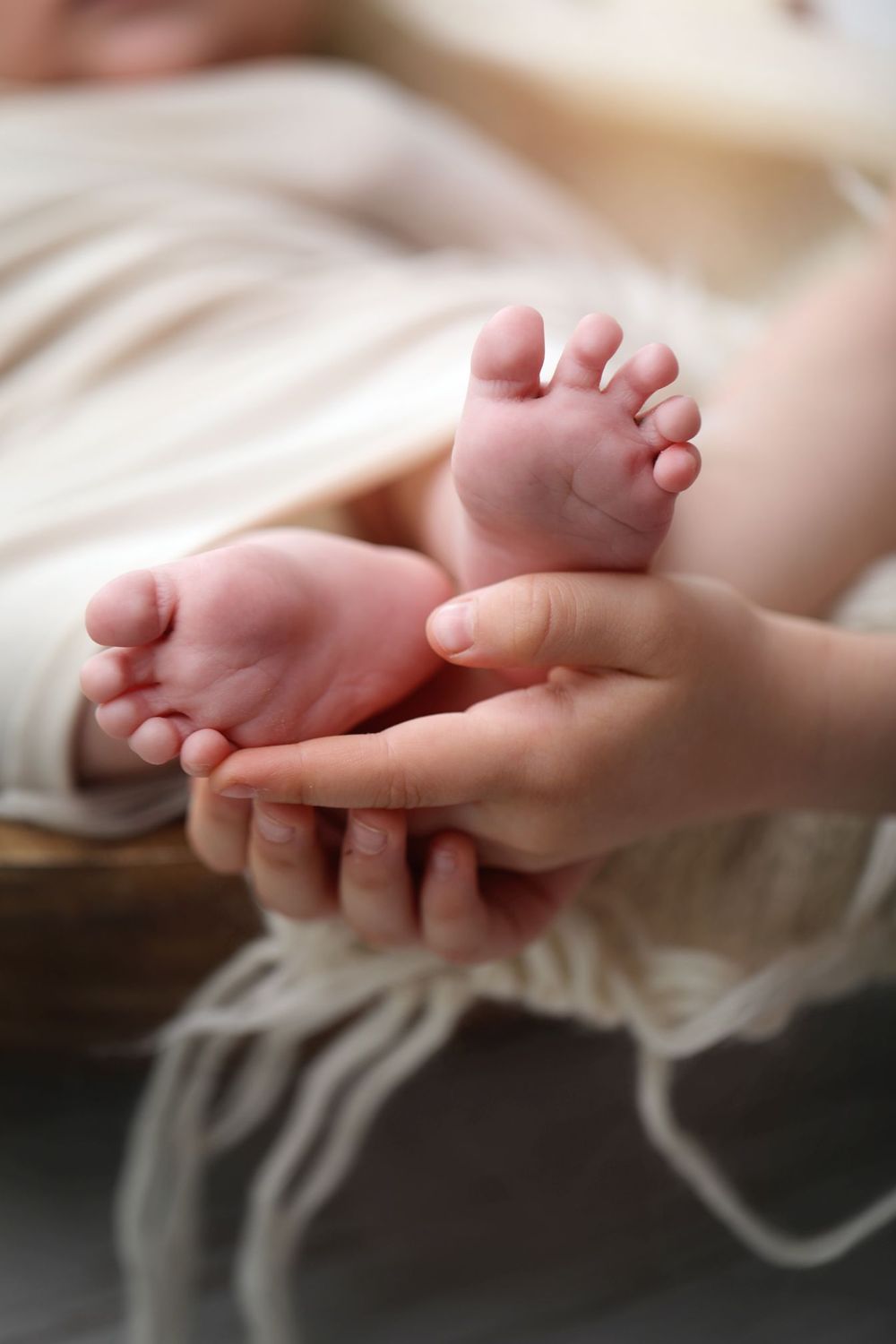 Close-up of tiny newborn baby feet being held in gentle hands.