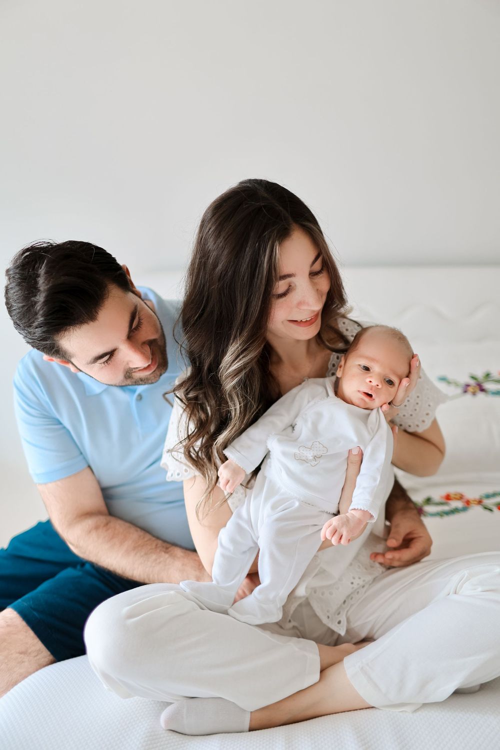 Tender family moment shared on white bedding in natural light.