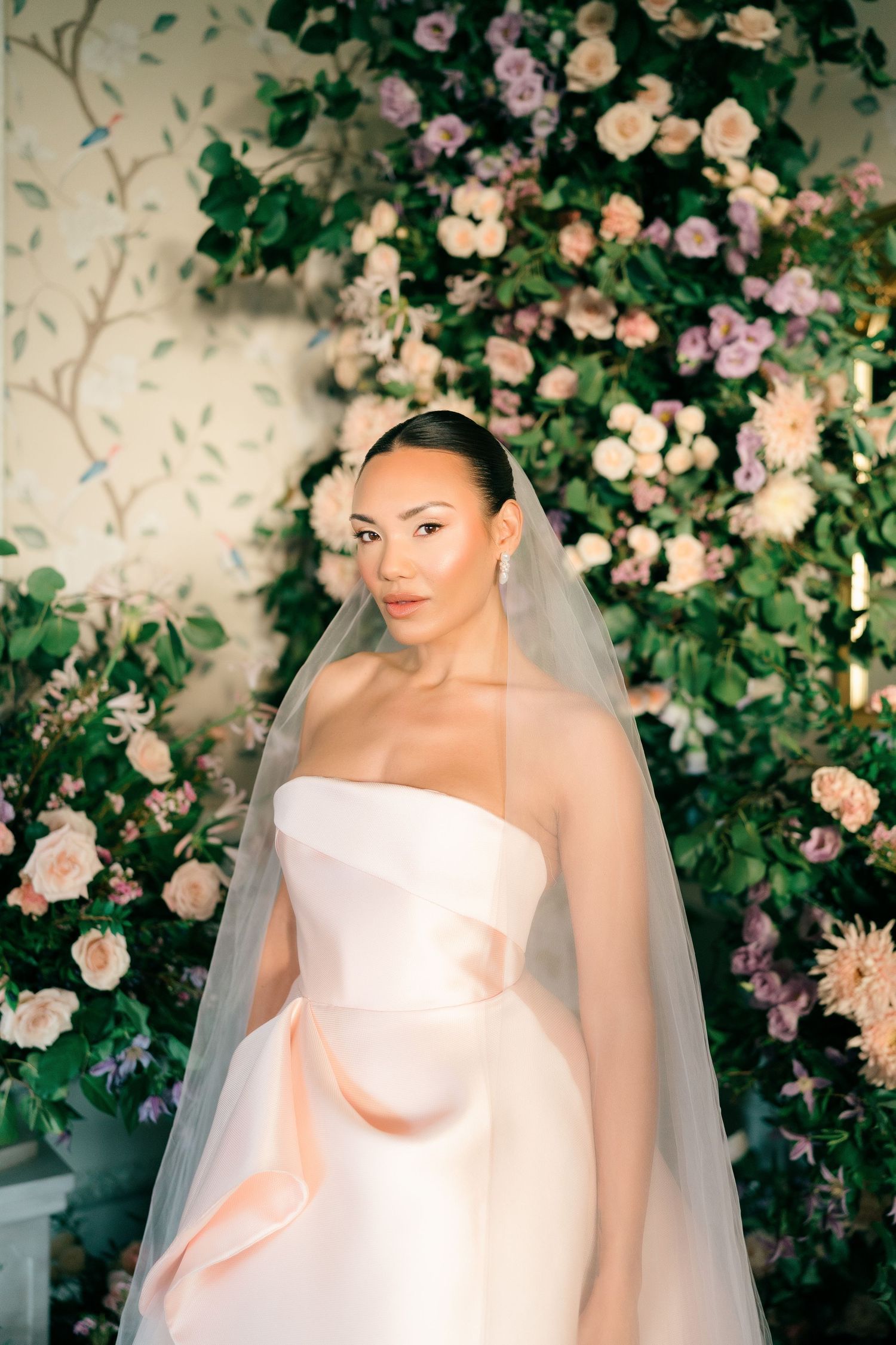 Romantic bridal portraits surrounded by blooming pink and peach roses.