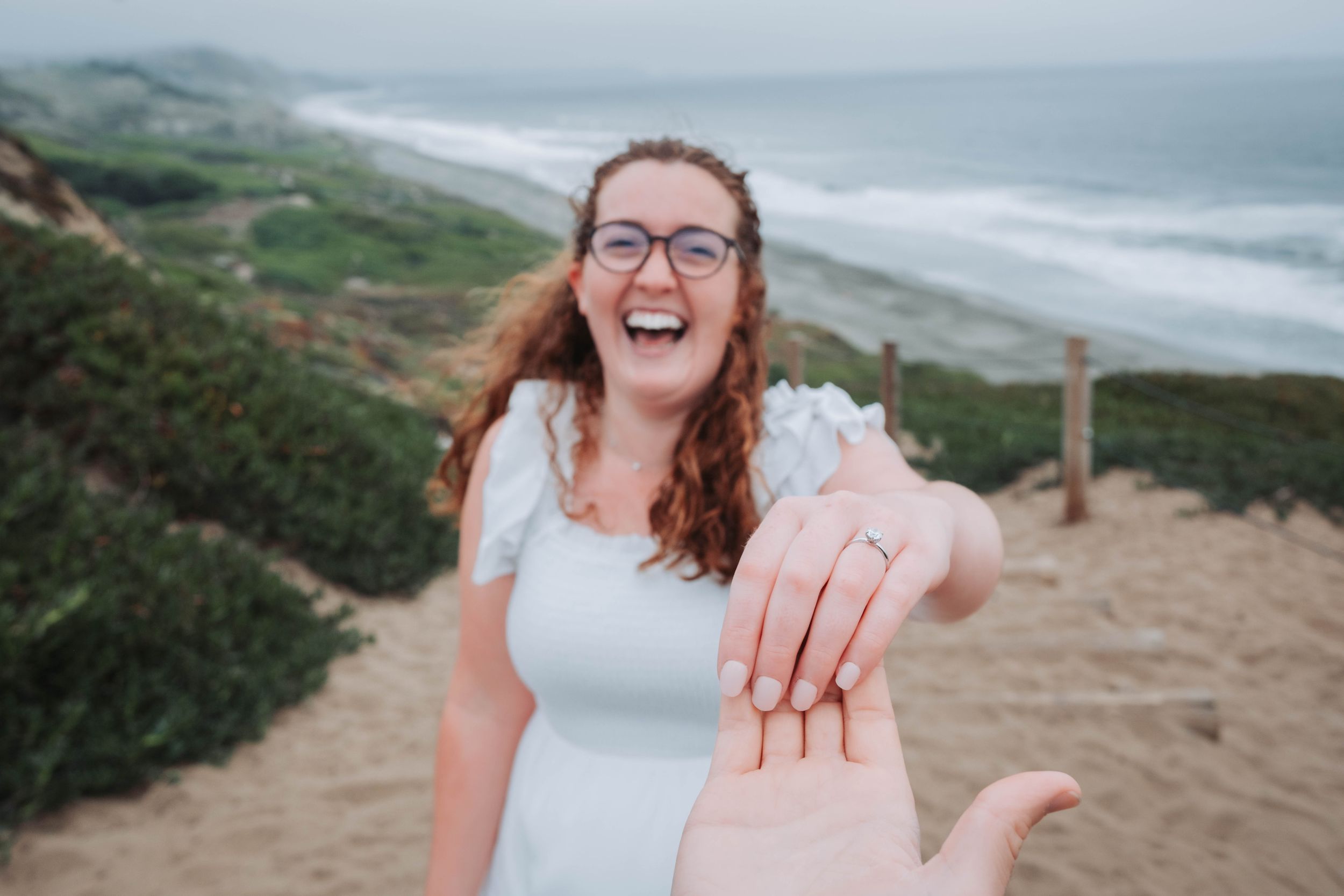 A series of photos showing a joyful engagement proposal moment at a scenic coastal overlook with ocean views.