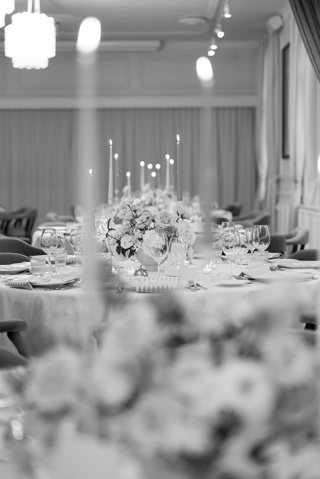 Elegant wedding reception table settings with crystal glassware and white floral centerpieces in a luxurious banquet hall.