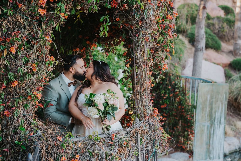 A couple shares a romantic moment under red berry trees during an outdoor wedding photoshoot.