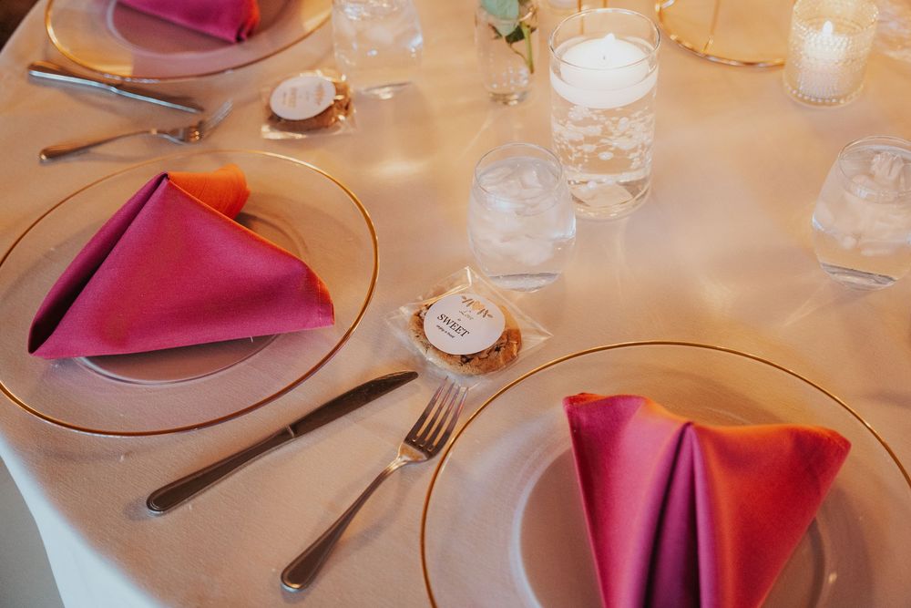 Elegant table settings with pink napkins and white tablecloths in a formal dining room.