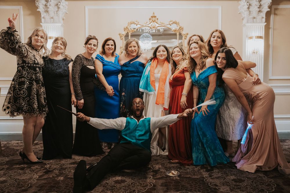 A group in formal attire poses together at an elegant venue with ornate wall decorations.