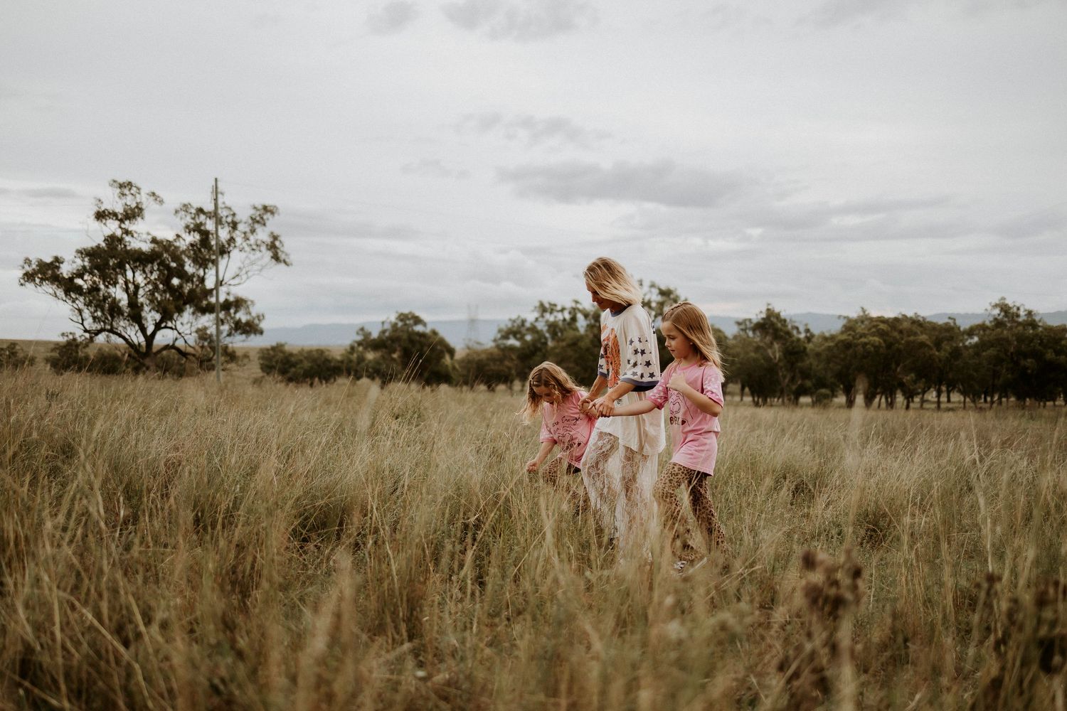 A family enjoying a tender moment together in a golden field at sunset with trees in the background.