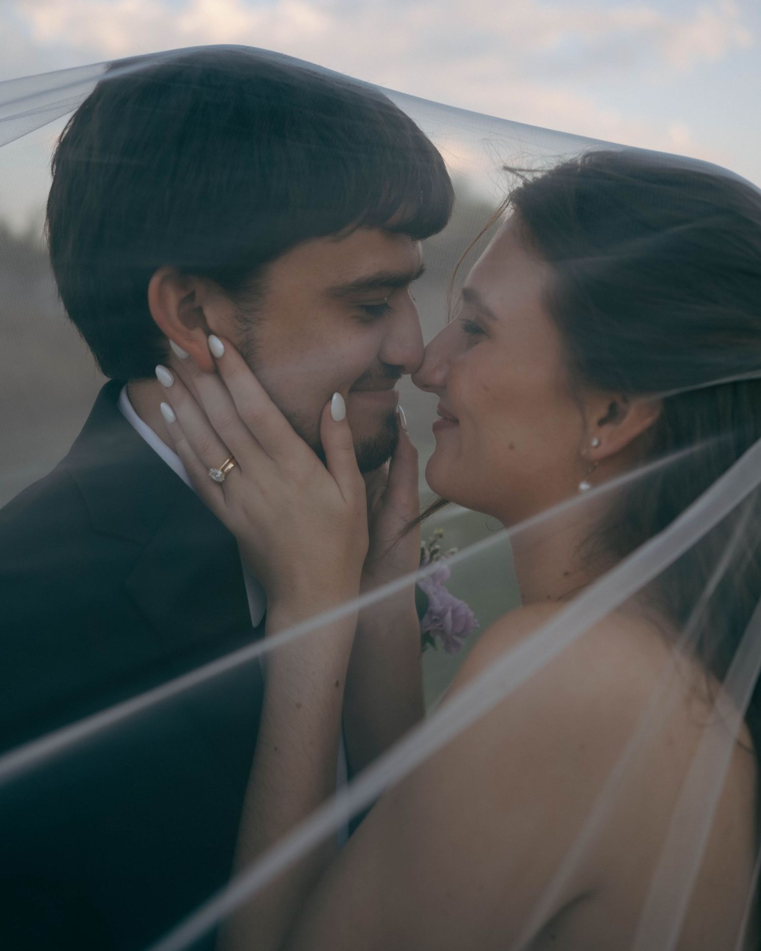 A romantic wedding moment captured through a delicate veil as the couple shares an intimate close-up embrace.
