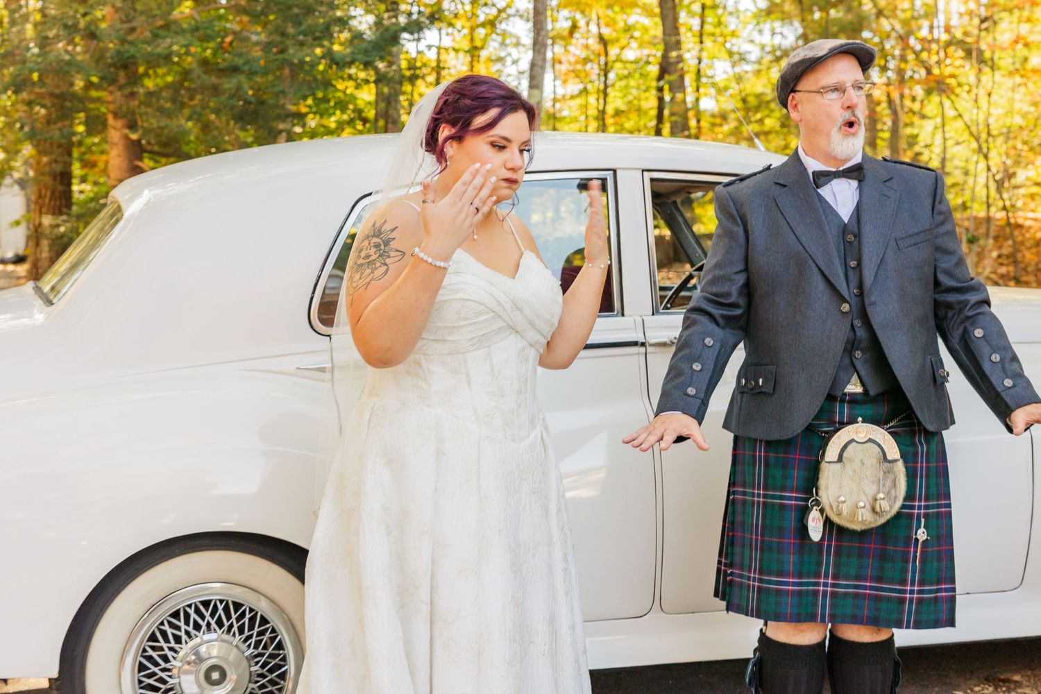 Wedding couple celebrates joyfully with guests on a beautiful autumn day with golden foliage in the background.