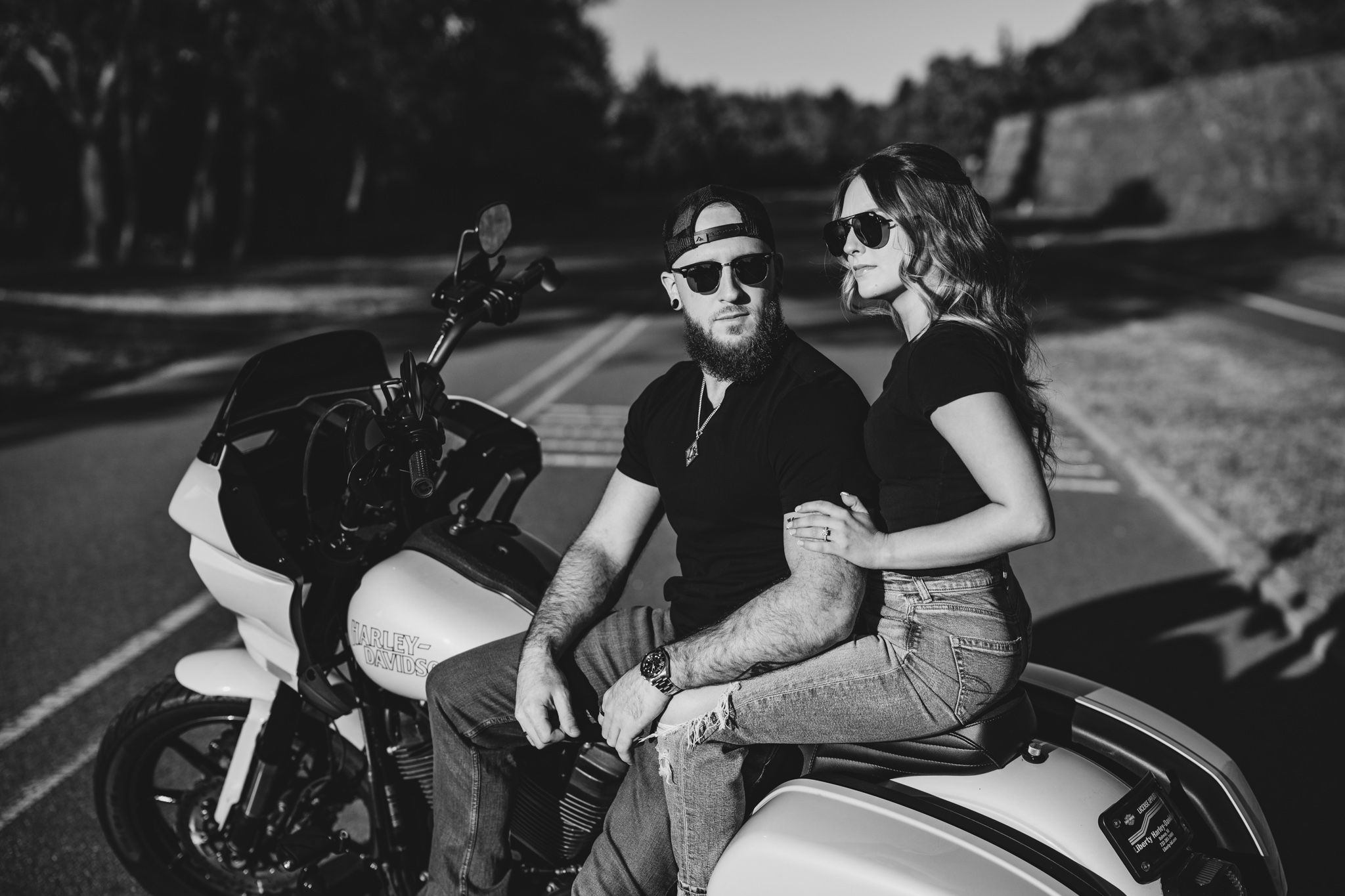 Motorcycle engagement session with couple in casual attire on parked bikes.