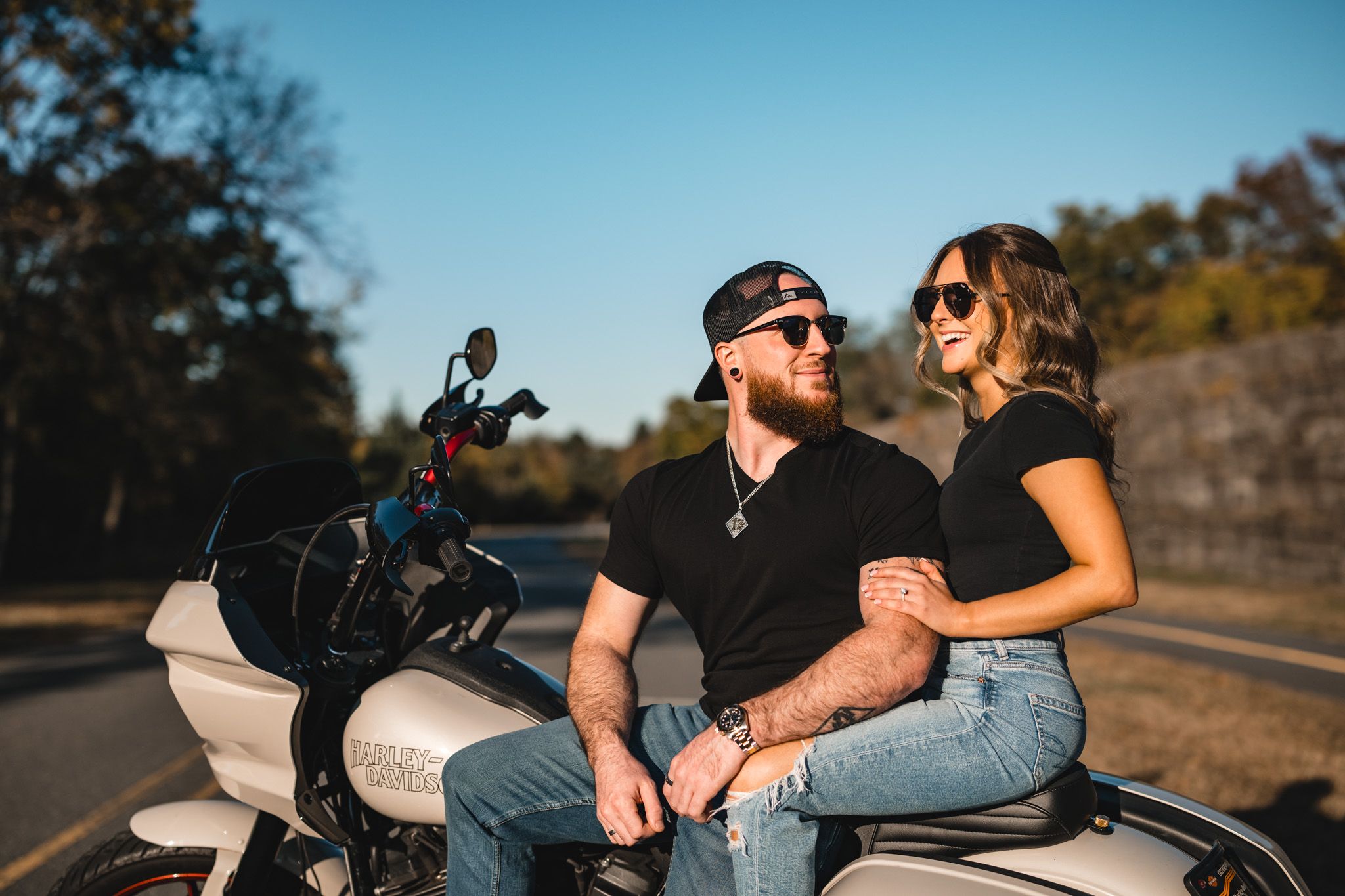 Couple relaxing on parked motorcycles during sunny afternoon ride.