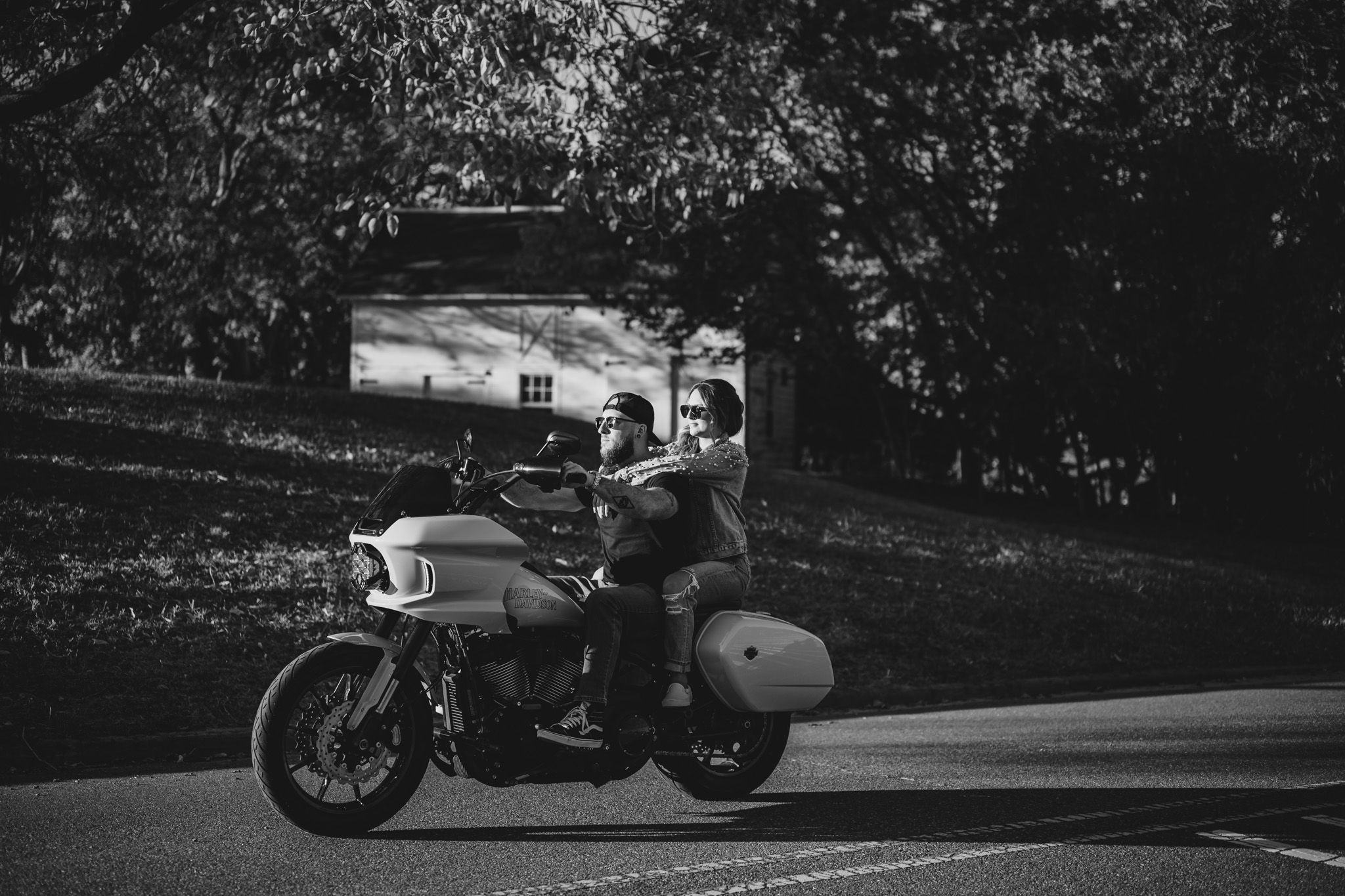 Silhouetted motorcycle parked on a dark road with trees in the background.