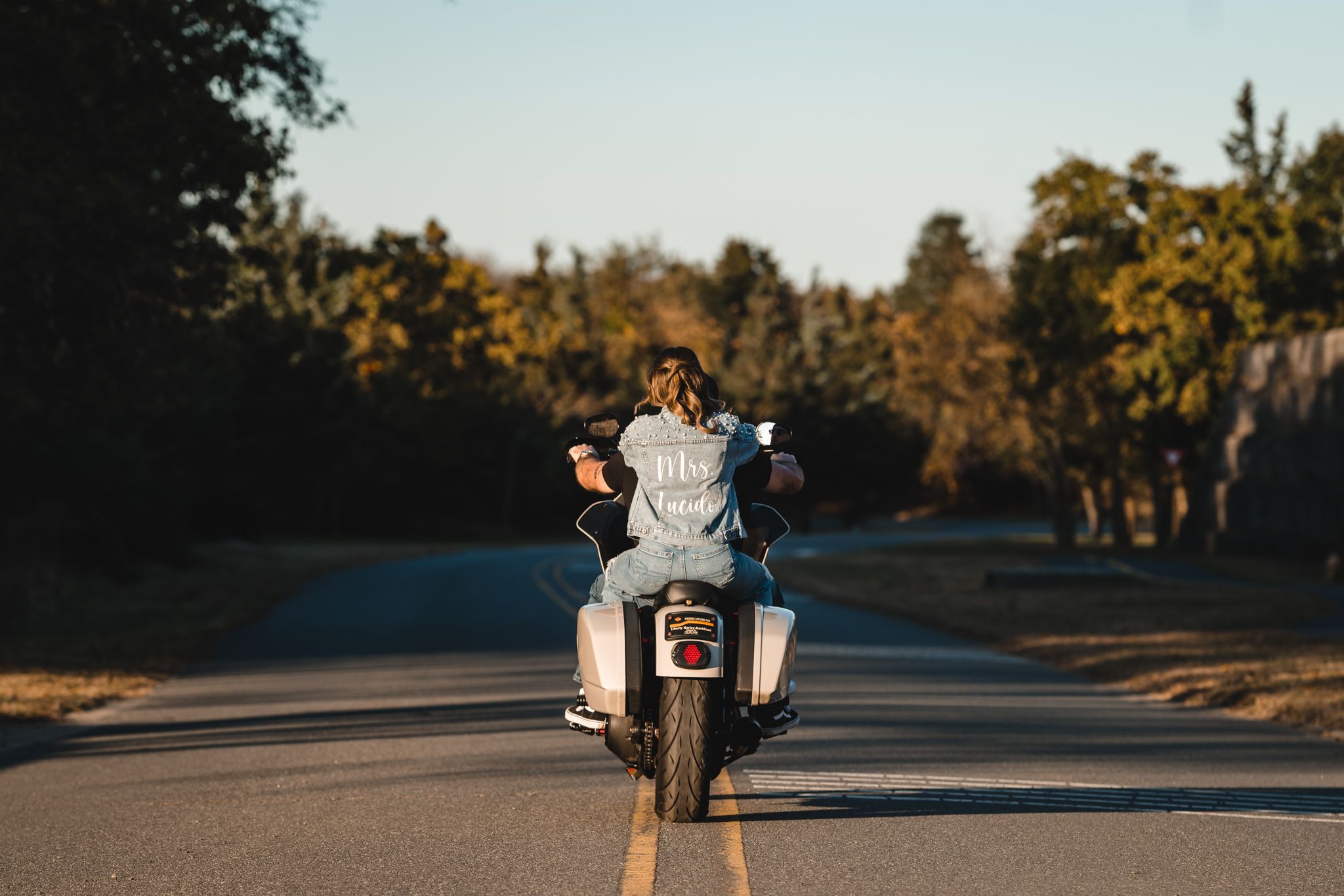 Motorcycle parked on a scenic road during golden hour with trees and nature in the background.