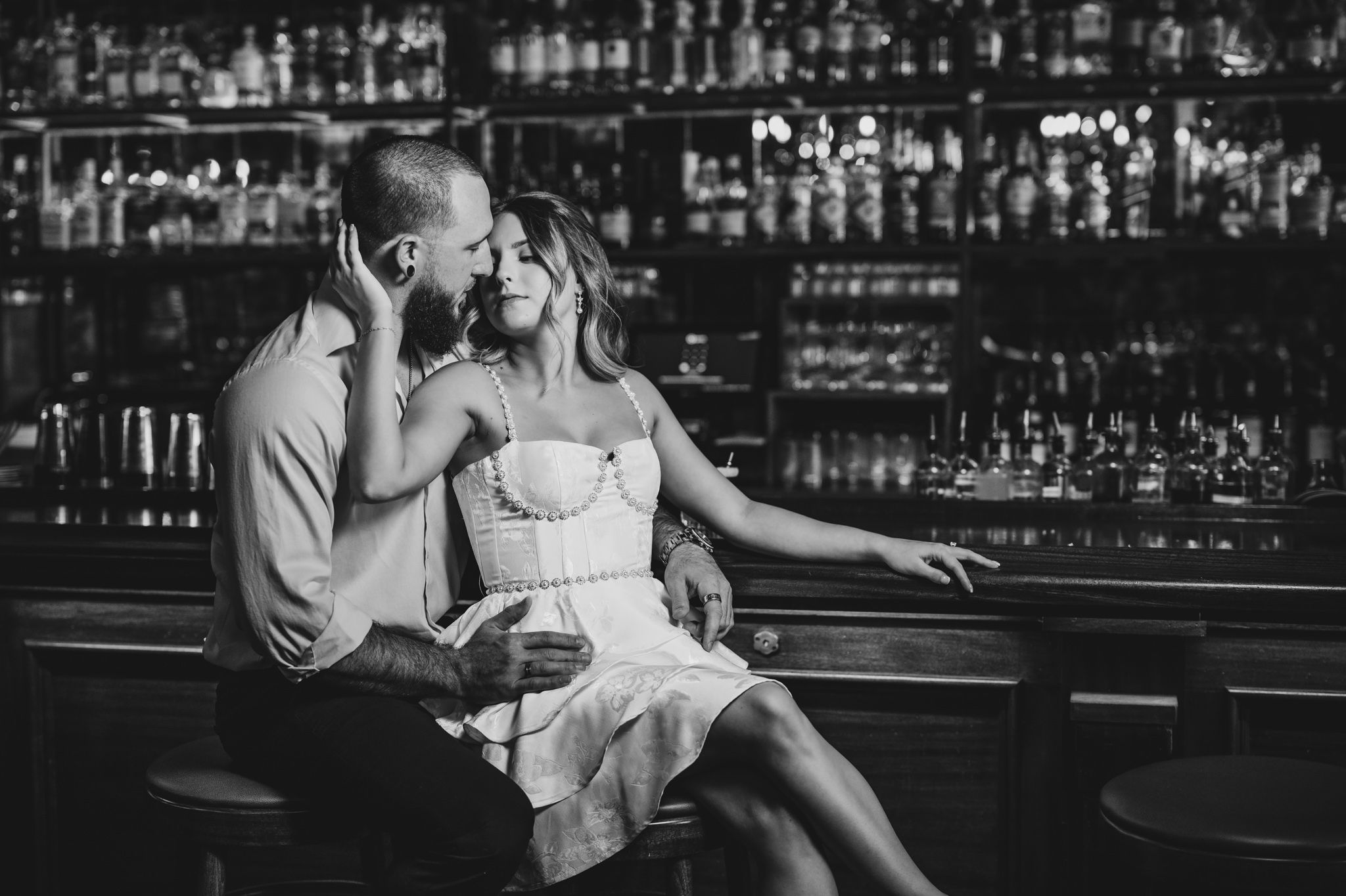 Black and white photos of couple at vintage bar counter with dramatic lighting.