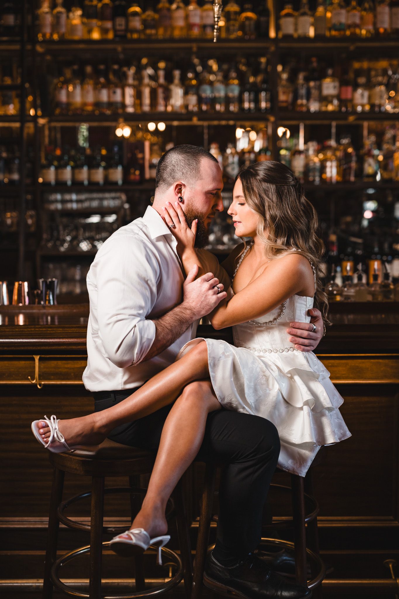 Playful couple sharing drinks and laughter at an elegant bar counter.
