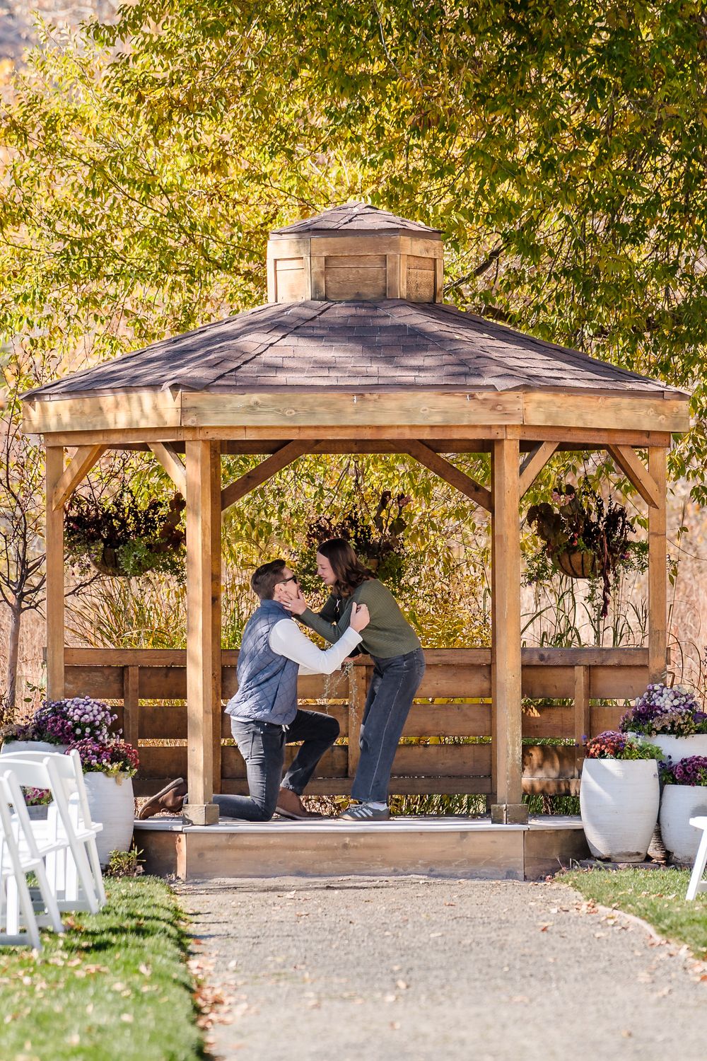 A panoramic view of wooden gazebos in a park setting with autumn foliage and gravel pathways.