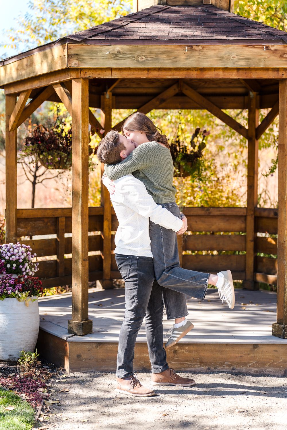 A romantic proposal unfolds in a rustic wooden gazebo surrounded by fall foliage.