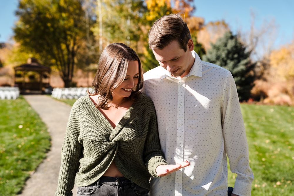 A couple shares an intimate moment in a garden setting during autumn.