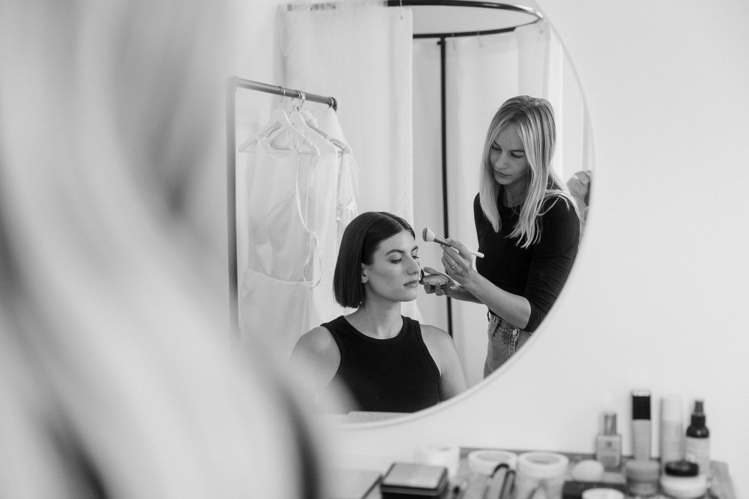 Black and white sequence showing hair styling session in a salon mirror.