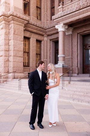 Couple poses outside historic stone building with columns.
