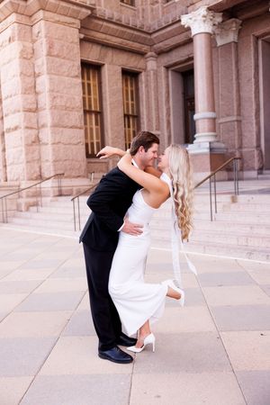 Romantic dip pose sequence outside limestone building.
