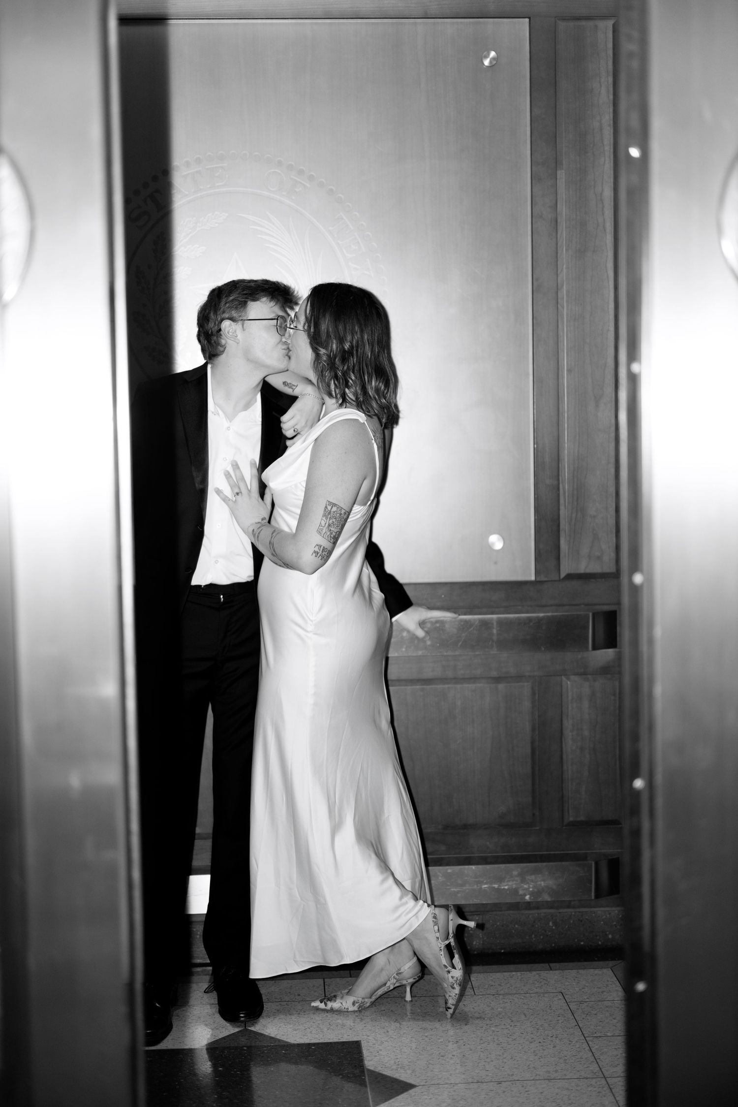 A black and white photo series captures intimate moments between a couple in a hallway.