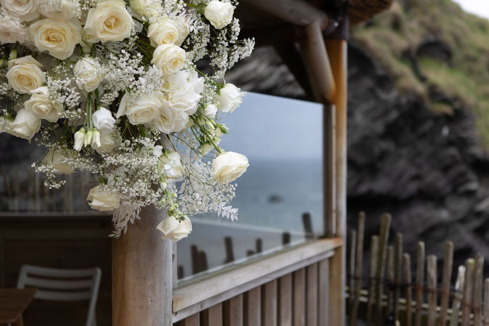 Close-up of white roses and baby's breath bouquet decorating a wooden wedding gazebo by the sea.