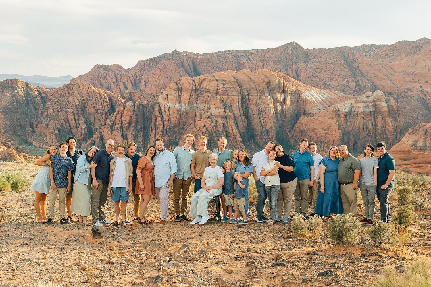Wide landscape shot of family gathering with desert mountains in background during golden hour.