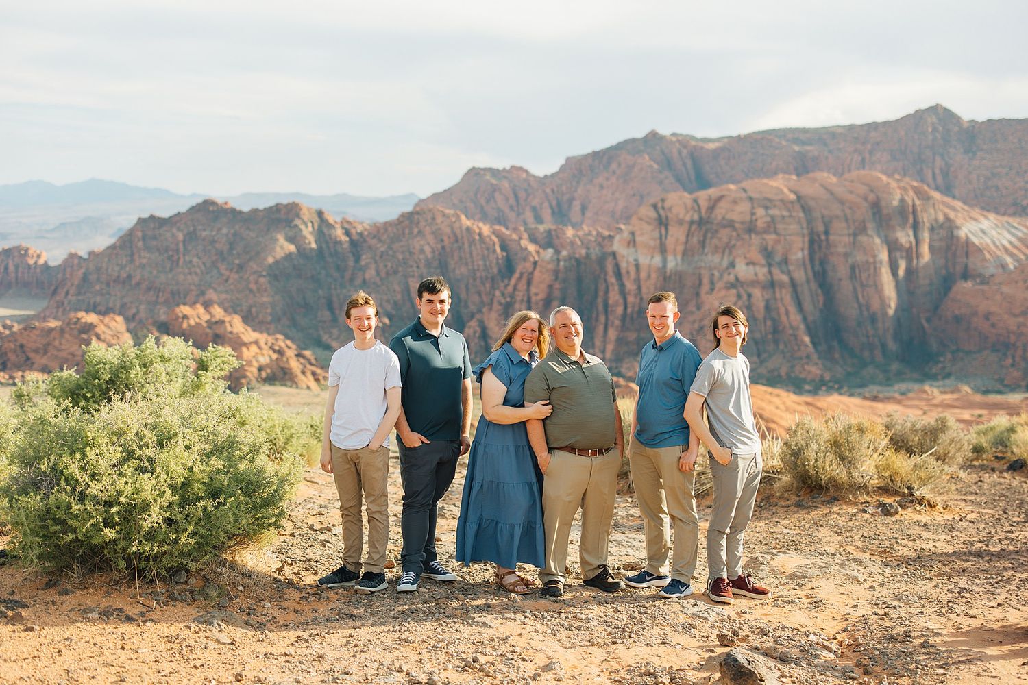Family sitting together on desert rocks with sweeping mountain views in the distance.