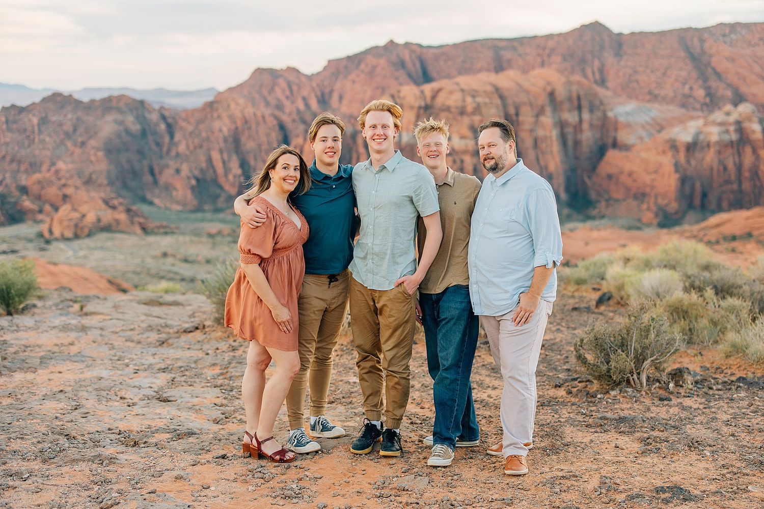 Extended family photo session among the red rocks and desert vegetation at sunset.