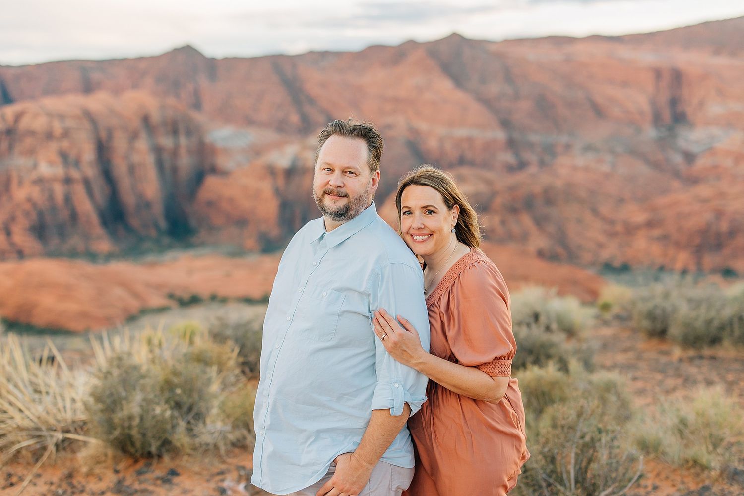 Casual outdoor photoshoot with desert mountains and brush creating a scenic backdrop.