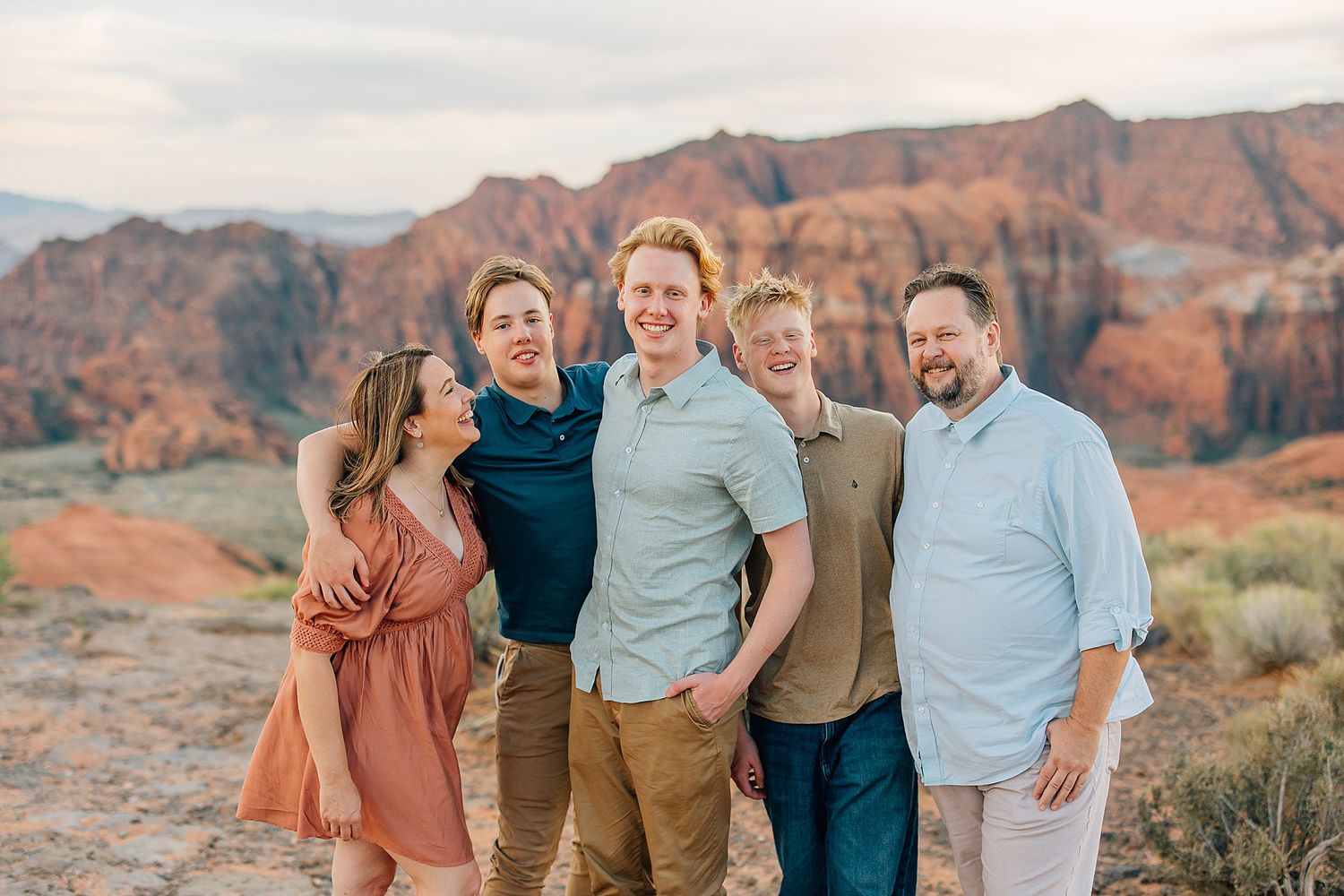 Candid family moments captured against dramatic desert cliffs and sage brush.