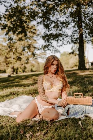 Romantic outdoor photography with cream lingerie and picnic setting under trees.