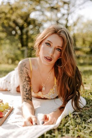 Outdoor boudoir photoshoot with dreamy golden lighting and white blanket on grass.