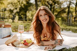 Sunny outdoor lifestyle shoot with picnic blanket and wine glass props.